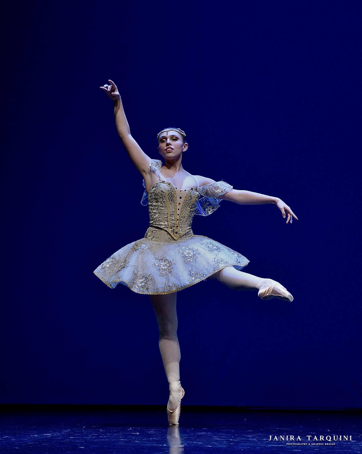 Ballerina classica in tutù avorio su un palcoscenico blu